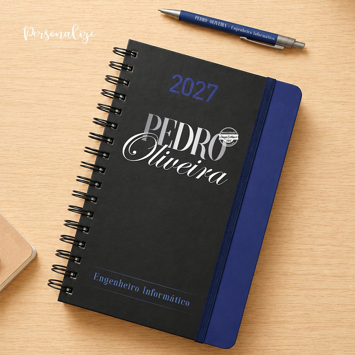 Organiza os teus dias com uma&nbsp;agenda diária personalizada com argolas, pensada para quem gosta de ter tudo planeado sem abdicar de um toque pessoal e cheio de significado. Com capa preta de design elegante, esta agenda combina a personalização do&nbsp;nome e profissão criando uma peça única e especial.

A agenda inclui&nbsp;argolas, permitindo uma utilização prática e confortável, e pode ser personalizada de acordo com o gosto de cada pessoa. A&nbsp;caneta personalizada com o nome&nbsp;complementa o co