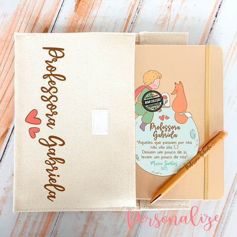 Novidade final das aulas!  Conjunto bolsa + Bloco de notas e caneta " Principezinho ". Surpreenda com um dos nossos conjunto com novo design do principezinho.   -Tamanho da bolsa : 25,5 x 17,5 cm, 310 grs com fecho velcro laminada no interior. -Bloco dourado com elástico, tamanho A5 com folhas lisas - Caneta metalizada dourada.  As 3 peças são personalizáveis!  REF: PRO501